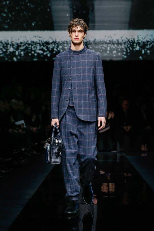 Présentée à Milan, la collection homme de Giorgio Armani mêle un vestiaire sportswear futuriste à la tradition du costume centrale à l’histoire de la maison. Bon nombre de costumes en laine déclinent le col Mao, à l’instar de ce trois-pièces à carreaux au boutonnage asymétrique.