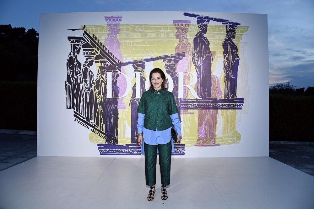 Amira Casar wore a Dior Winter 2021-2022 green silk blouse and pant with a Dior Spring-Summer 2021 blue silk shirt and Dior sandals. She also wore a Dior Caro light green leather bag.   
