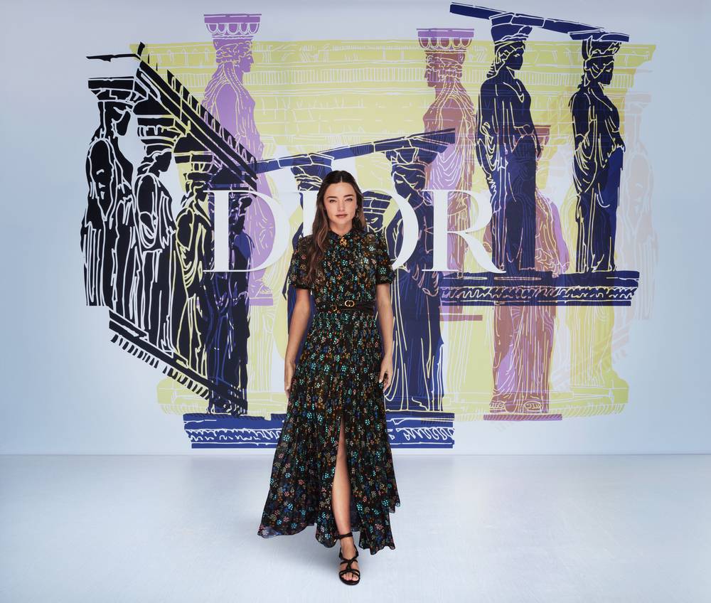 Miranda Kerr wore a Dior Pre Fall 2021 printed black silk dress with a Dior belt and Dior sandals.