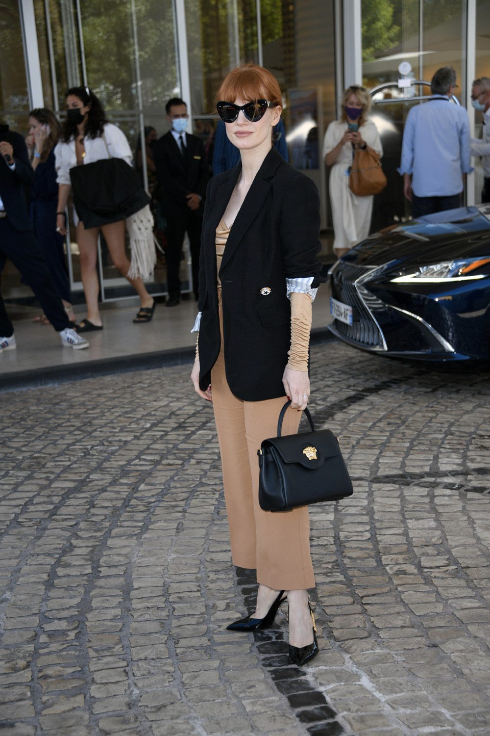 Jessican Chastain en pantalon, veste, blouse et sac Versace.
