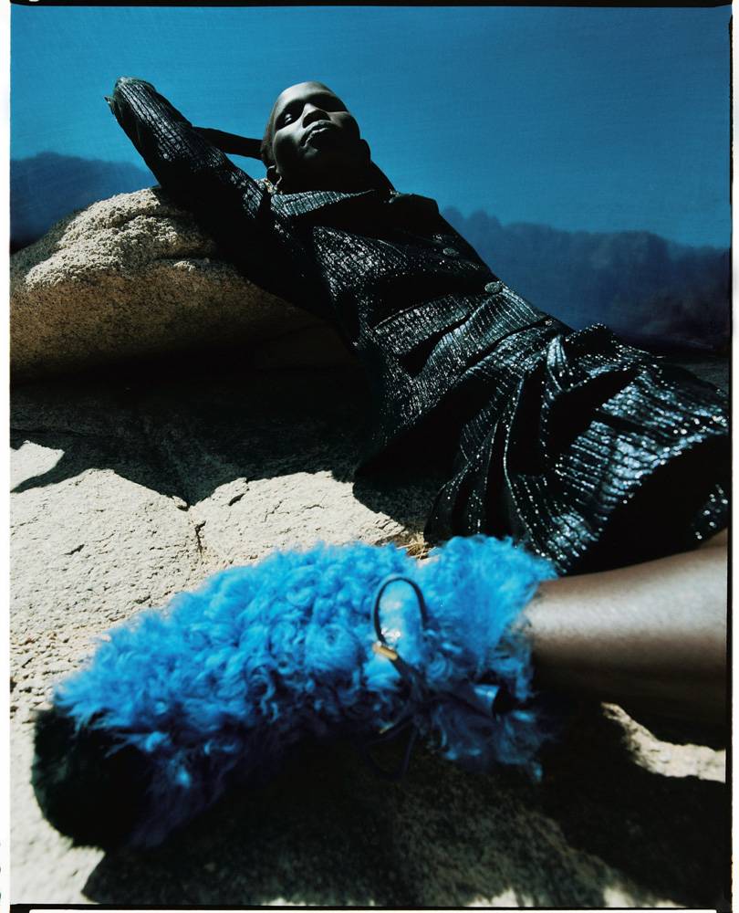 Shanelle Siase photographiée par  Dan Beleiu porte une Veste et jupe en toile irisée, bottes et boucles d’oreilles, CHANEL.