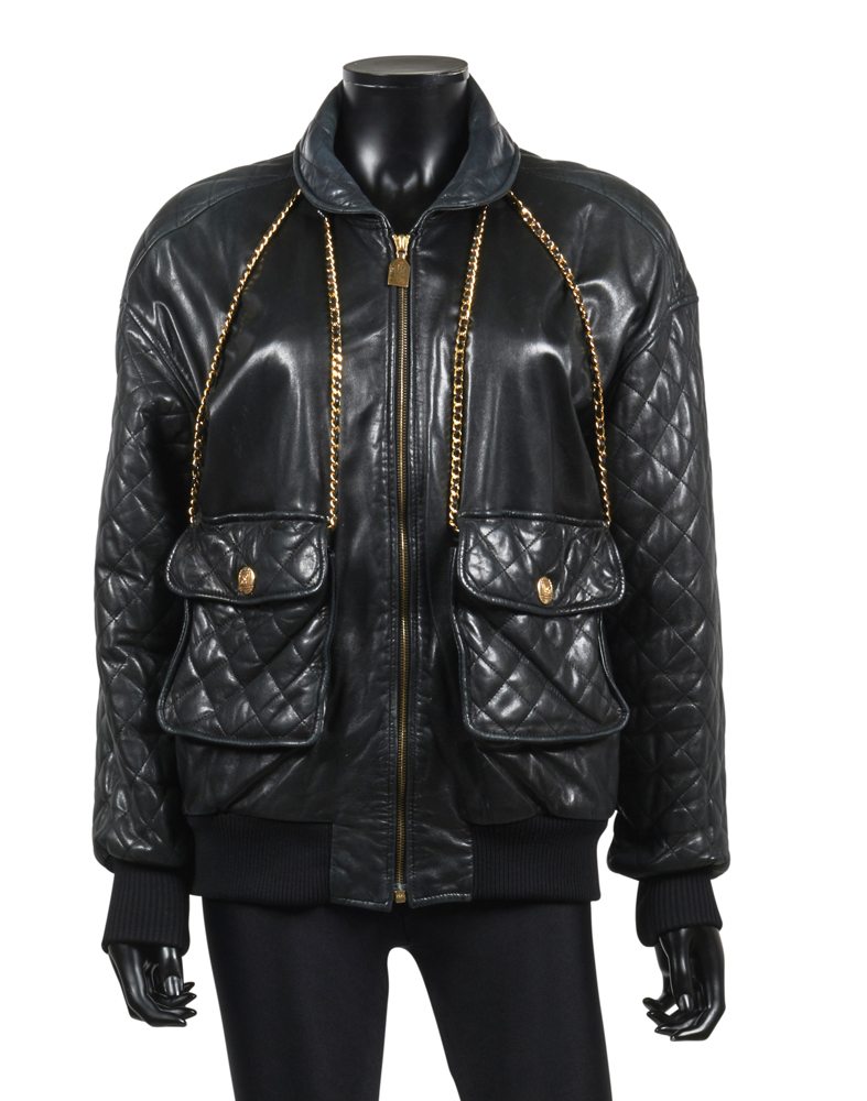 Chanel Boutique, Veste trompe-l'œil en cuir partiellement matelassé noir, chaînes amovibles entrelacées de cuir allant du col aux poches, boutons siglés en métal doré, estimation : 500/800€