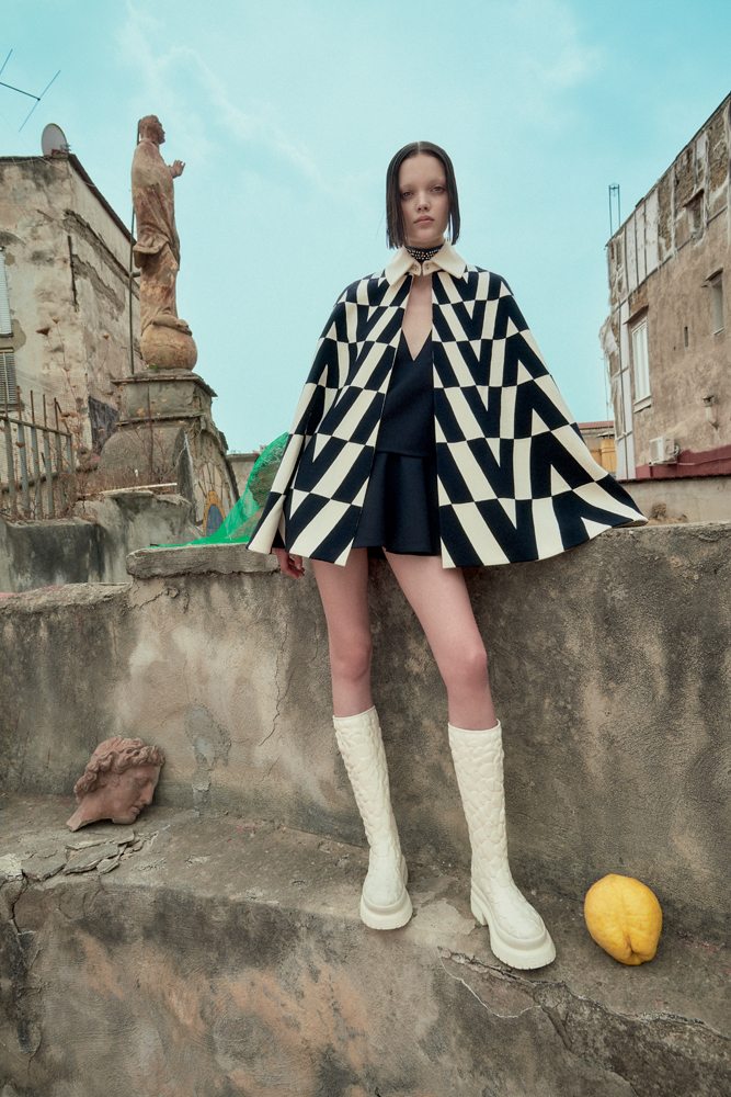 La mannequin Shayna McNeill dans la série “Sur les toits” par Sofia Sanchez et Mauro Mongiello. Cape en laine, robe en crêpe et organza, et bottes, VALENTINO.