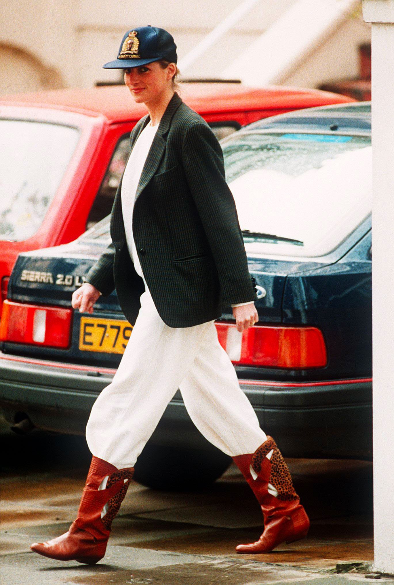 Princess Diana in 1989, wearing a stunning ensemble of wide white trousers, a blazer layered over a sweatshirt, and cowboy boots © Photo by Daily Mirror/Mirrorpix/Getty Images