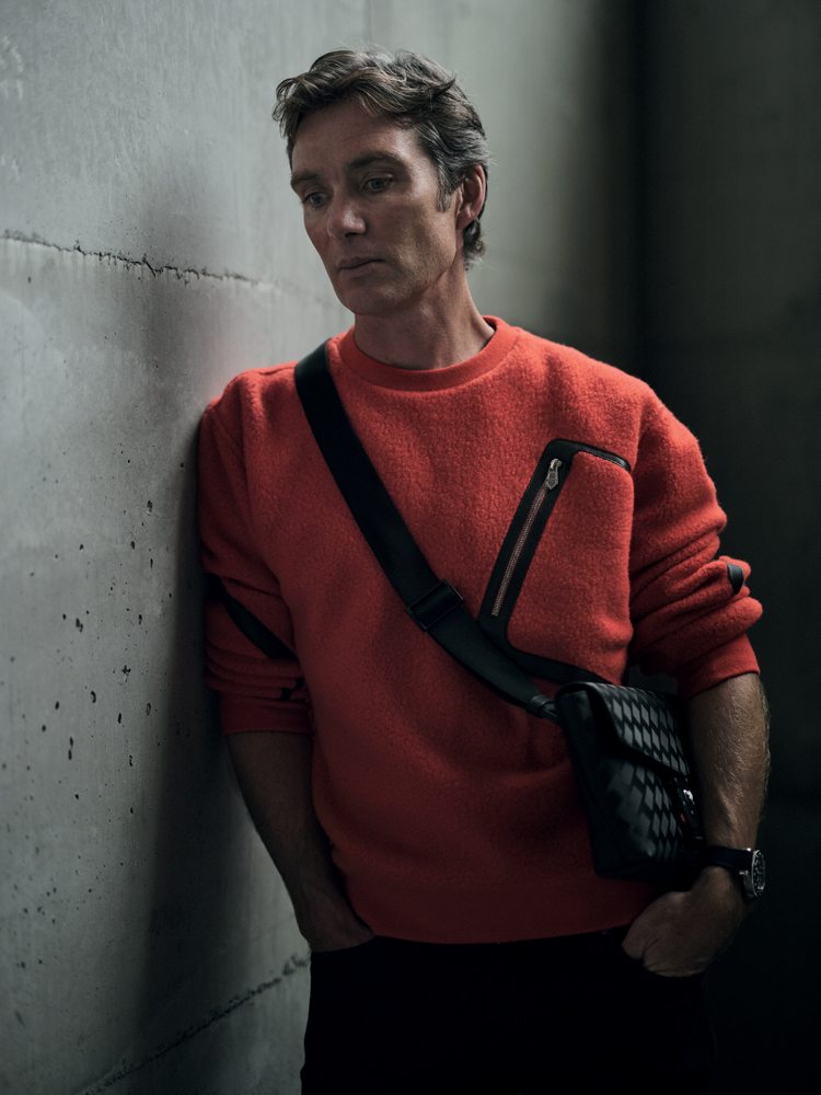 Cillian Murphy in wool and cashmere teddy sweater and cotton canvas pants, HERMÈS. Pouch bag and watch “Montblanc 1858 GMT”, MONTBLANC.