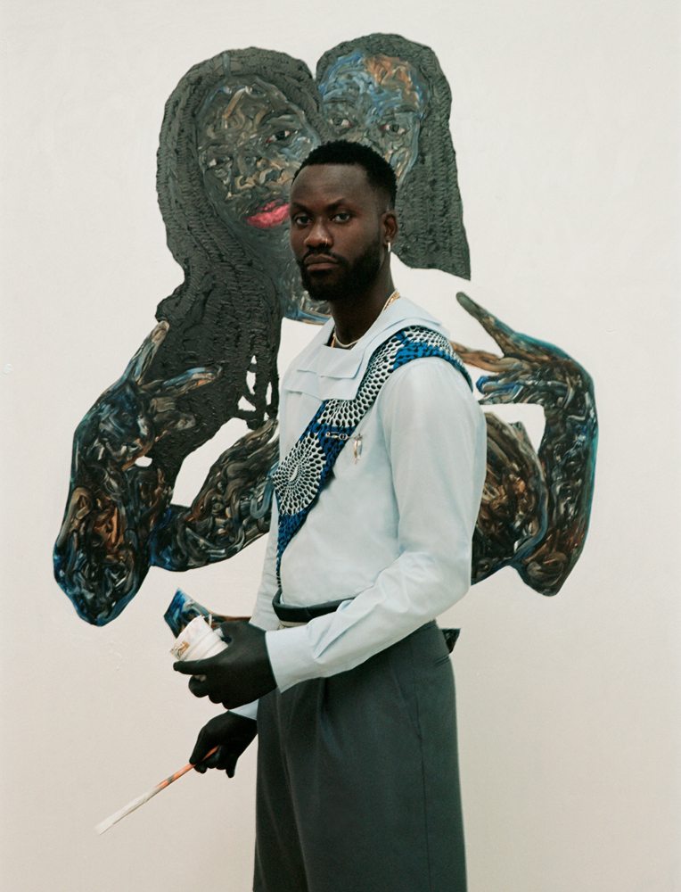Amoako Boafo devant Peace Out (2022, huile sur toile, 196 x 170 cm). Chemise à
col marin en popeline de coton, bermuda en flanelle de laine et broche, DIOR MEN. Bijoux et tissu vintage.