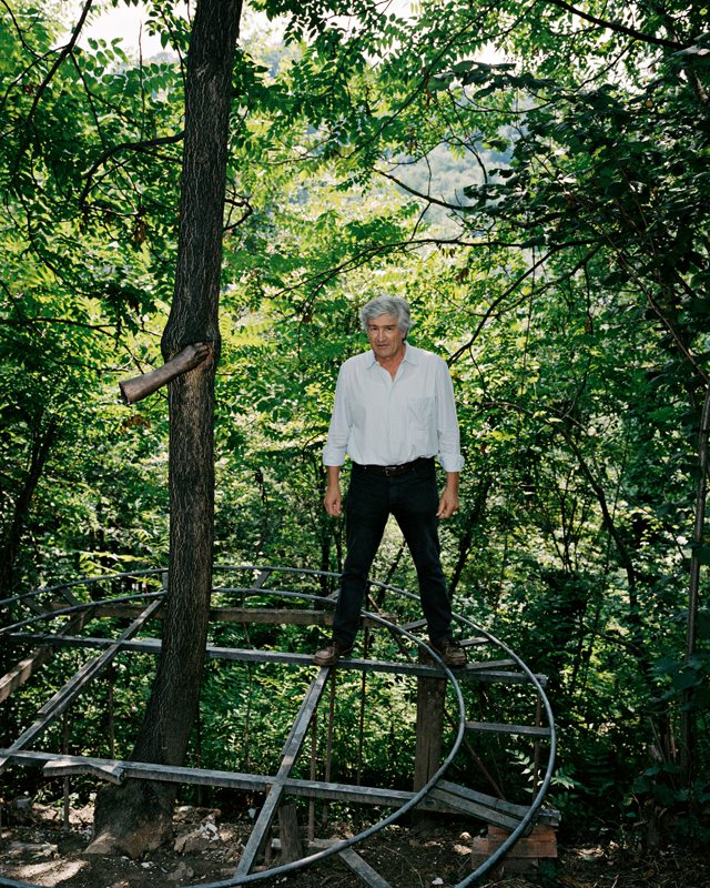 Giuseppe Penone pose à côté de son œuvre inaugurale de 1968, reproduite dans sa forêt près de Turin. Il a maintenu le tronc d'un arbre avec sa main, moulée en acier. La croissance lente de l'arbre est marquée par cette présence, le tronc adaptant son parcours.