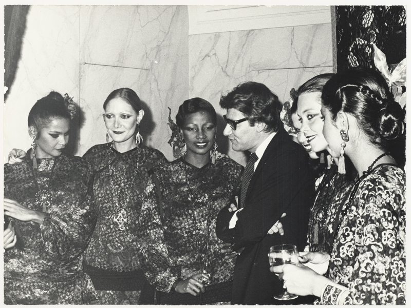 Yves Saint Laurent en 1977, entouré de ses mannequins, lors de la soirée organisée pour le lancement français du parfum Opium, 5, avenue Marceau, à Paris. 

