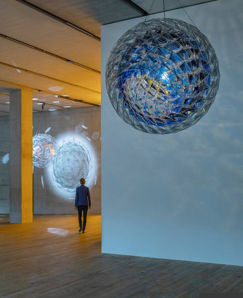 <p>Vue de l’exposition <em>In Real Life</em> à la Tate Modern, Londres, 2019 avec l’oeuvre : Olafur Eliasson, <em>Cold wind sphere </em>(2012), Acier inoxydable, verre teinté (bleu sombre, bleu et vert clair), miroir, filtre de verre (bleu), bulbe, Diamètre : 170 cm. Collection du Centre Pompidou, MNAM-CCI, Paris / © 2012 Olafur Eliasson / Photo : Anders Sune Berg</p>
